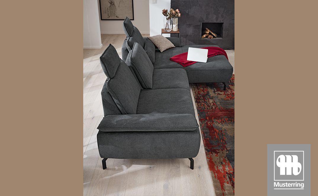 Graues Sofa mit verstellbaren Rückenlehnen und Longchair in stilvoll eingerichteter Wohnumgebung.