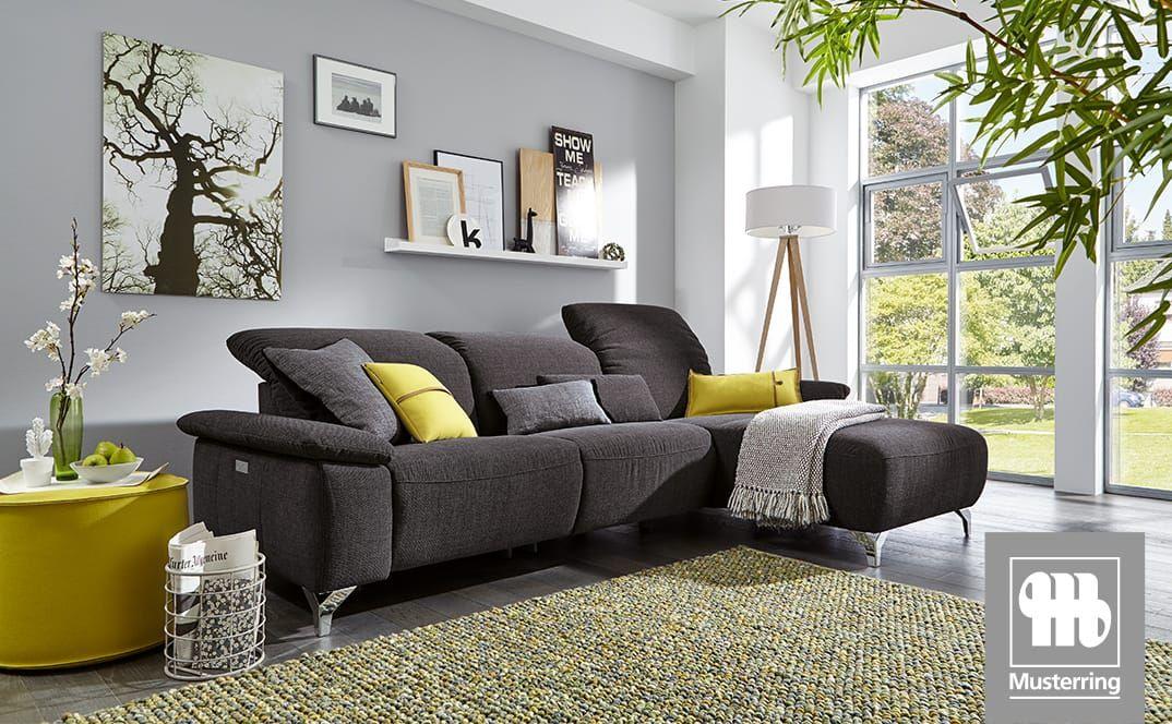 Dunkelgraues Ecksofa mit gelben Kissen in modernem, lichtdurchflutetem Wohnzimmer.