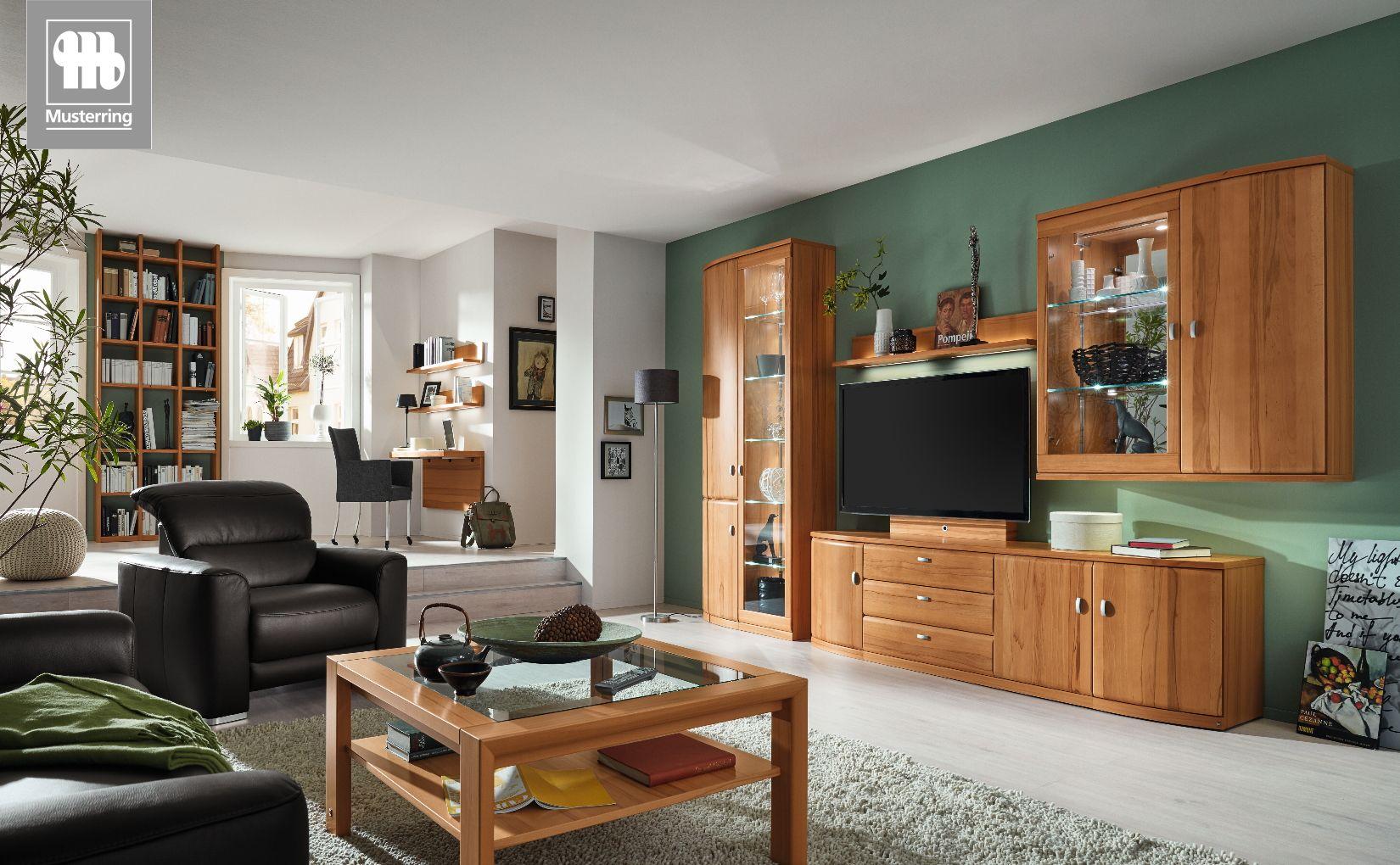 Wohnwand Kiana von Musterring mit Glashängeelementen und TV-Board vor grüner Wand