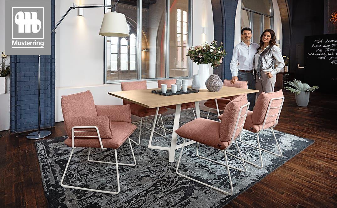 Essgruppe mit rosa Stühlen und Holztisch in hellem Raum.