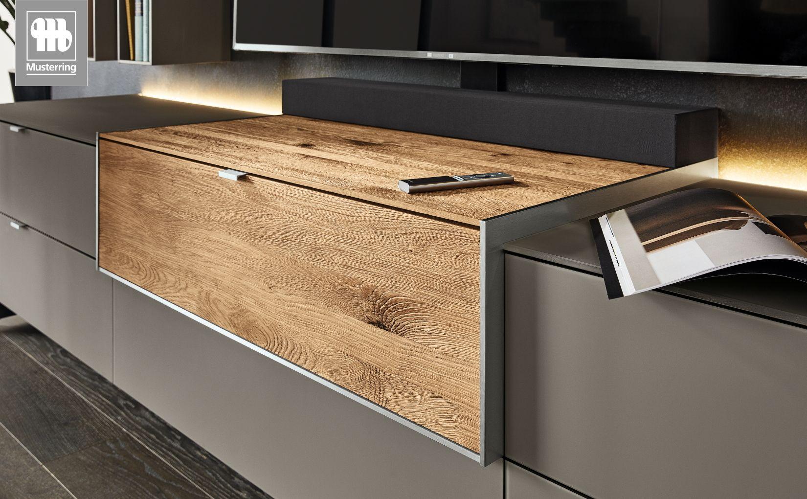 Detailansicht des Q-Media-Lowboards von Musterring mit Holzklappe und moderner Beleuchtung.