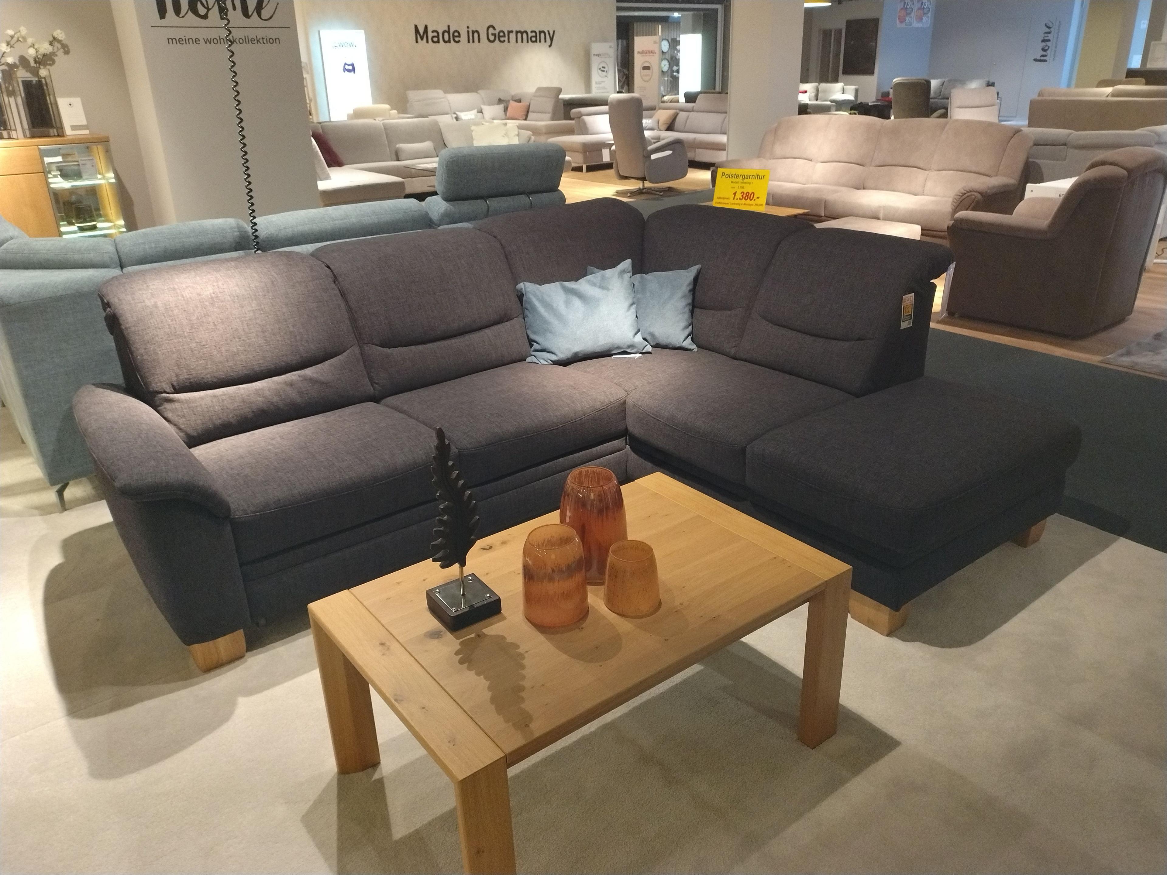 Polstergarnitur in dunklem Stoff mit davorstehend Armlehne links und offenem Abschluss rechts