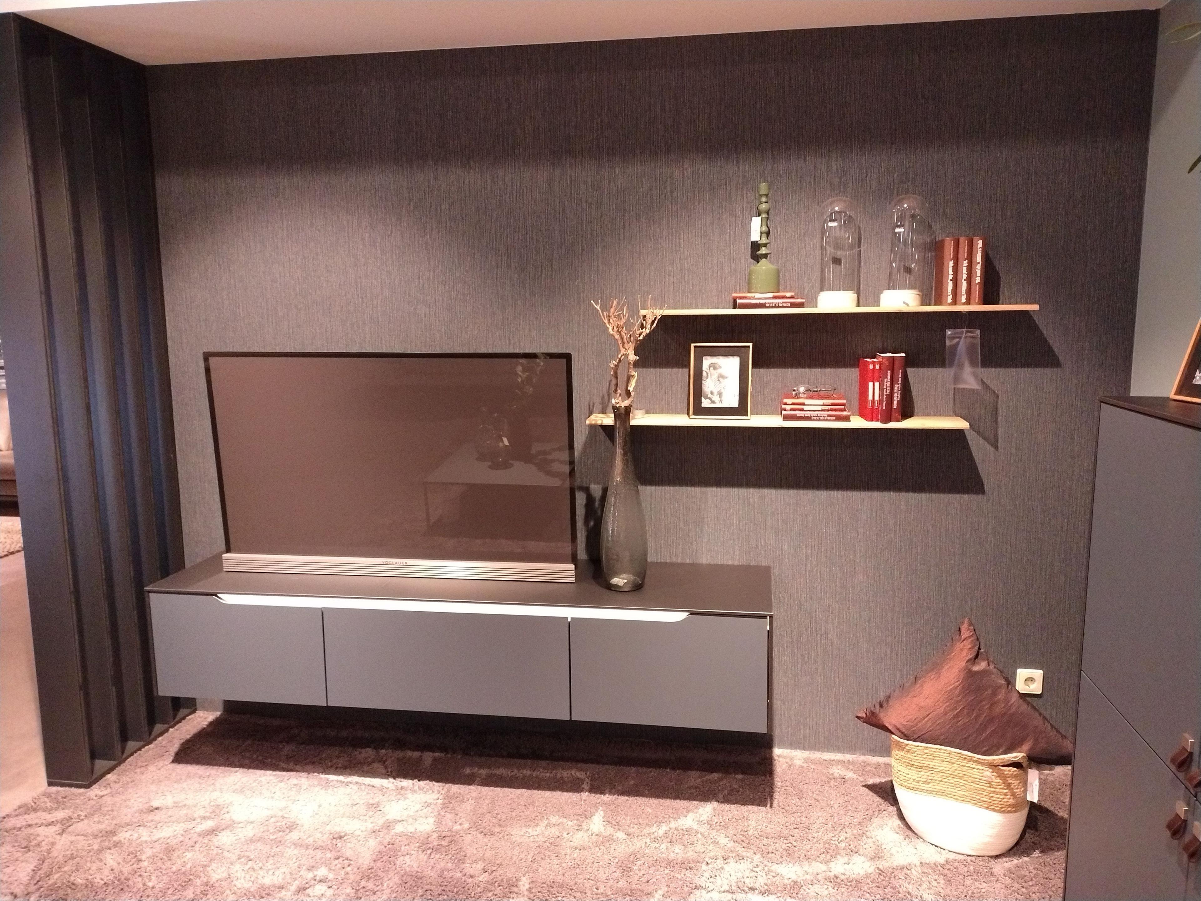 Wohnwand mit hängendem TV Lowboard beleuchtet in Fjordblau und zwei Wandboards in Eiche Sierra Nachbildung