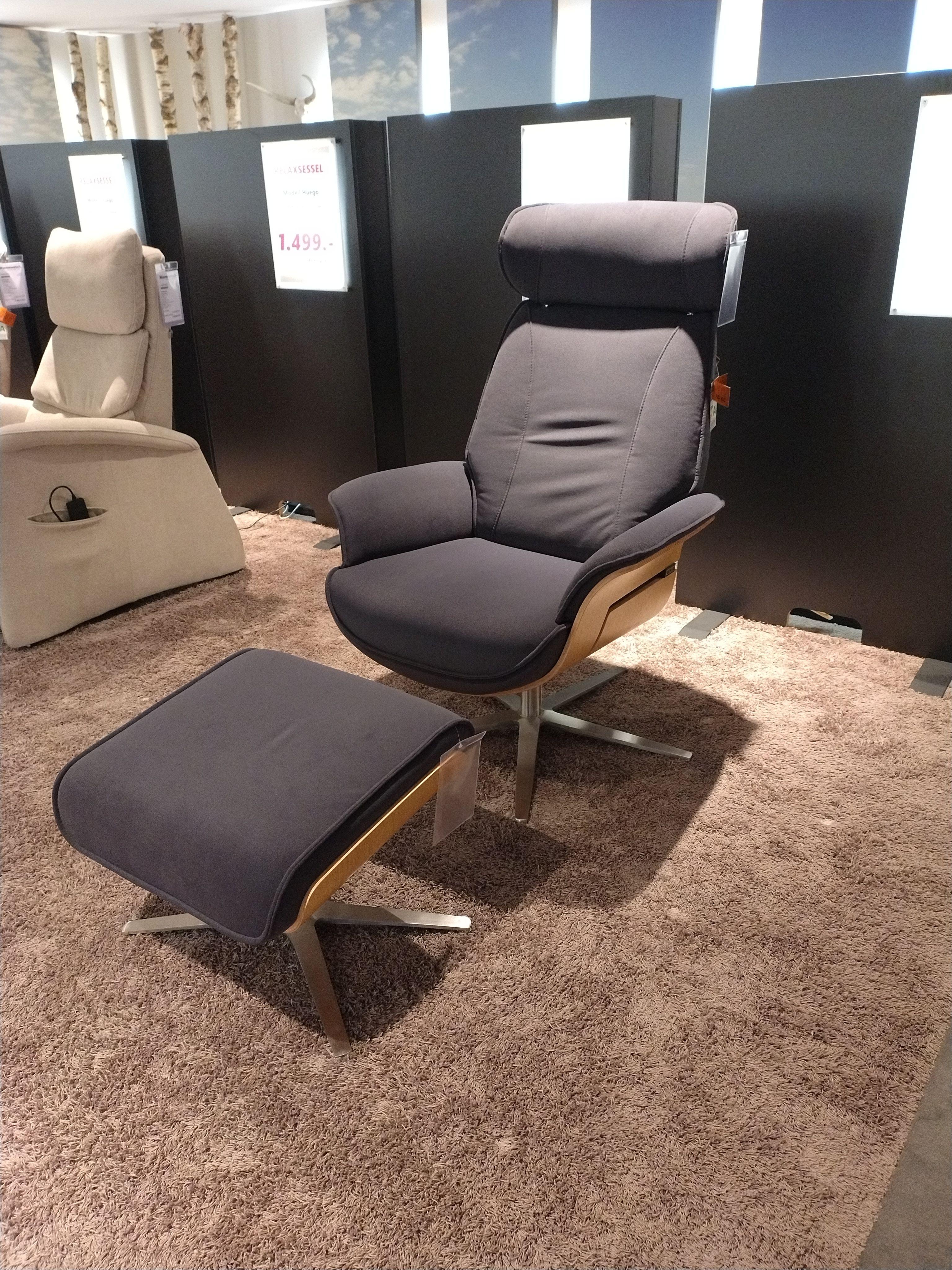 Relaxsessel mit Holzchatouse und Fußhocker einzeln davor stehend in grauem Stoff