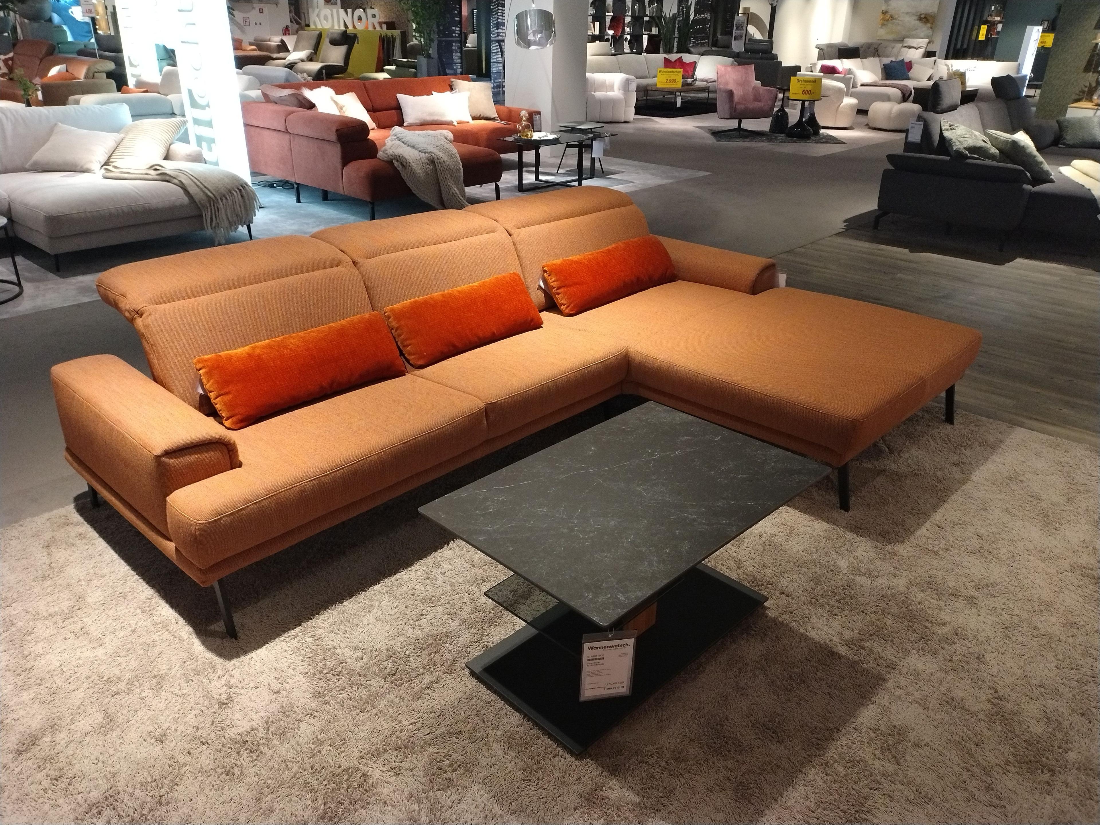 Sofa mit Armlehne links und breitem Longchair rechts in Stoff Farbe orange mit der Nierenkissen in anderem Stoff aber auch orange